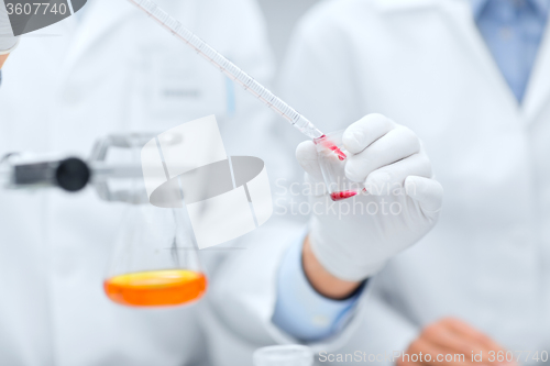 Image of close up of scientists filling test tube in lab