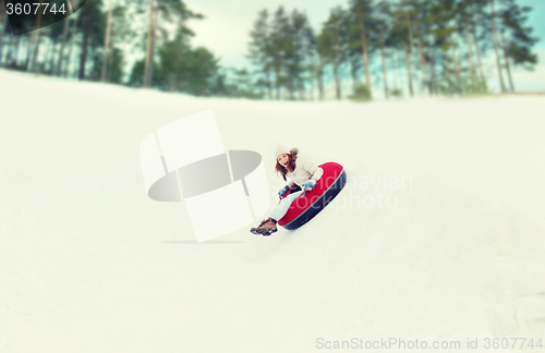 Image of happy teenage girl sliding down on snow tube