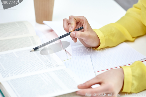 Image of close up of female hands with book and notebooks