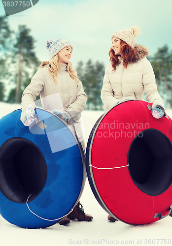 Image of happy girl friends with snow tubes outdoors