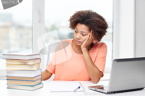 Image of bored african american woman doing homework home