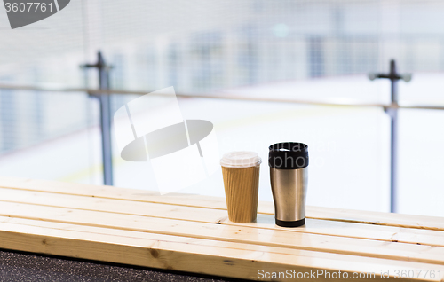 Image of coffee and thermos cup on bench at ice rink arena