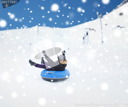 Image of happy young man sliding down on snow tube