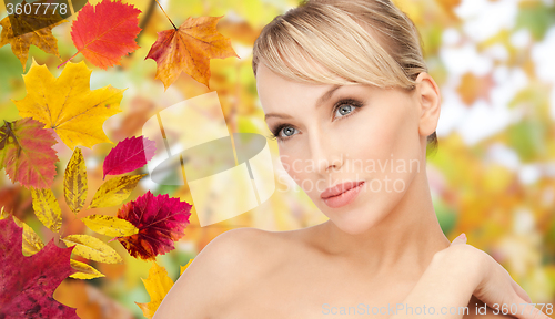 Image of beautiful young woman face over autumn leaves