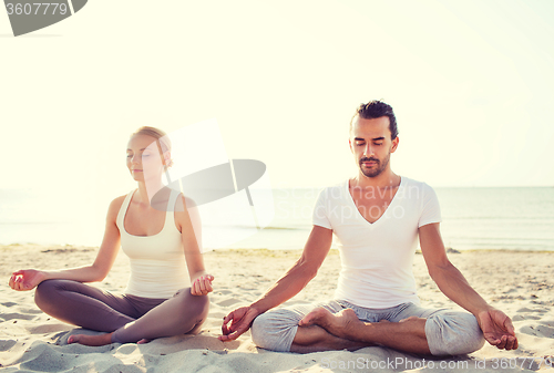 Image of smiling couple making yoga exercises outdoors