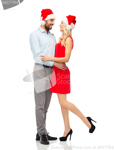 Image of happy couple in santa hats hugging