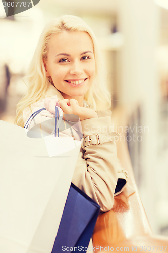 Image of happy young woman with shopping bags in mall