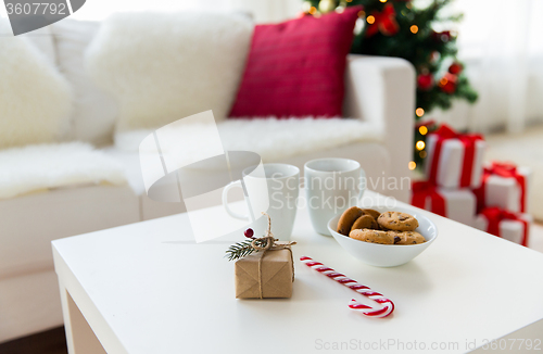 Image of close up of gift, sweets and cups on table at home