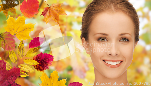 Image of beautiful young woman face over autumn leaves