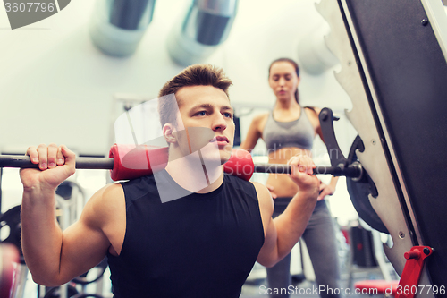 Image of man and woman with barbell flexing muscles in gym