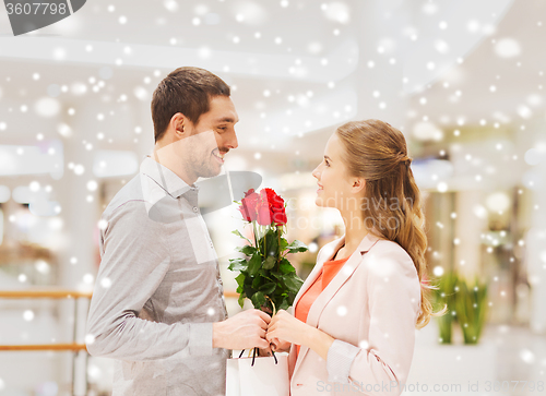 Image of happy young couple with flowers in mall