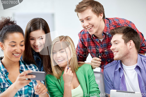 Image of group of happy students with smartphone at school