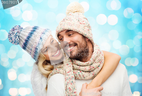 Image of happy couple in winter clothes hugging over lights