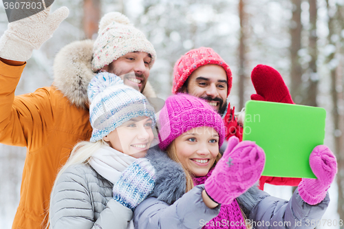 Image of smiling friends with tablet pc in winter forest