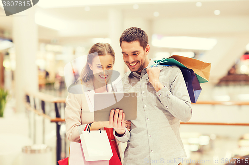 Image of couple with tablet pc and shopping bags in mall