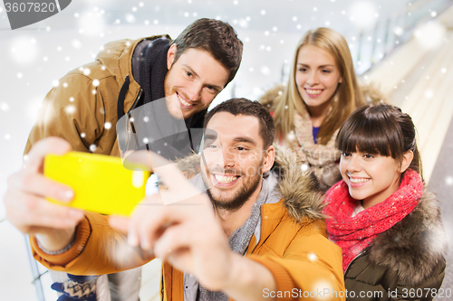 Image of happy friends with smartphone on skating rink