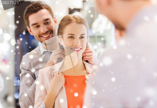 Image of couple trying golden pendant on at jewelry store