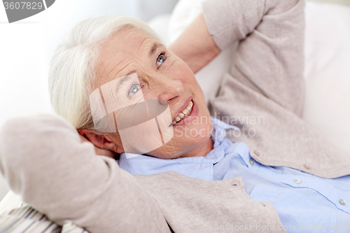 Image of happy senior woman resting on sofa at home
