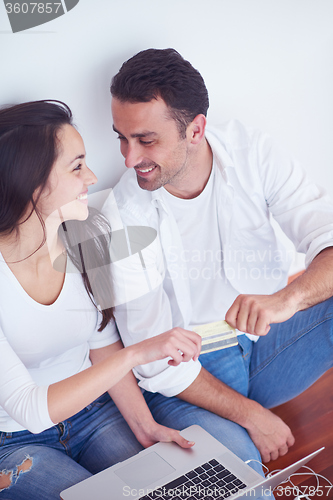 Image of relaxed young couple working on laptop computer at home