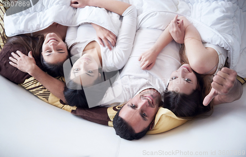 Image of handsome man in bed with three beautiful woman