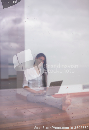 Image of relaxed young woman at home working on laptop computer