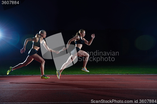 Image of athletic runners passing baton in relay race