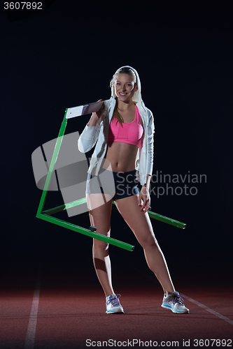 Image of woman athlete jumping over a hurdles