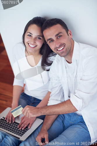 Image of relaxed young couple working on laptop computer at home