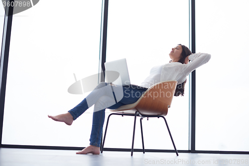 Image of relaxed young woman at home working on laptop computer