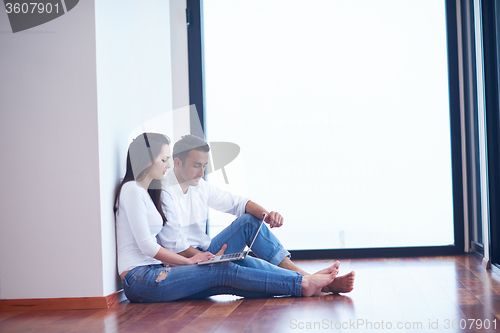 Image of relaxed young couple working on laptop computer at home