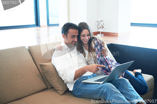 Image of relaxed young couple working on laptop computer at home