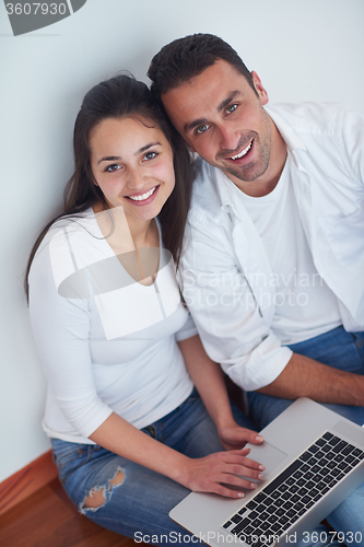 Image of relaxed young couple working on laptop computer at home