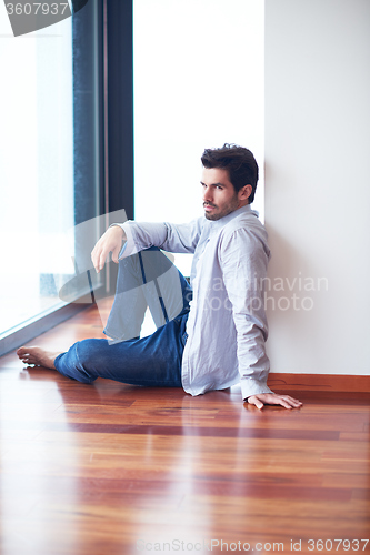 Image of relaxed young man drink first morning coffee withh rain drops on