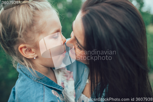 Image of The young mother and daughter on green grass background 