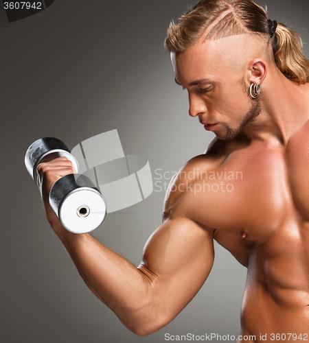 Image of Closeup of a handsome power athletic man bodybuilder doing exercises with dumbbell 