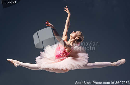 Image of Beautiful female ballet dancer jumping on a gray background