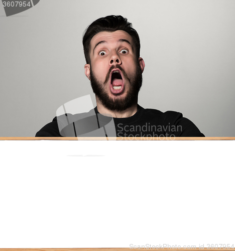 Image of The surprised man and empty blank over gray background