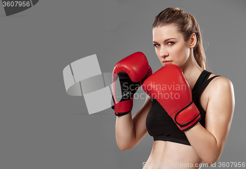 Image of beautiful woman is boxing on gray background