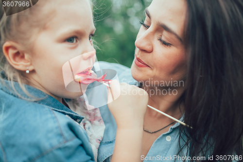 Image of The young mother and daughter on green grass background 