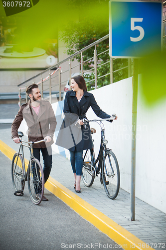 Image of Young couple with a bicycle opposite city 