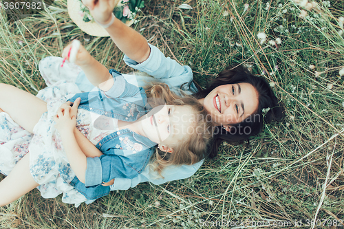 Image of The young mother and daughter on green grass background 