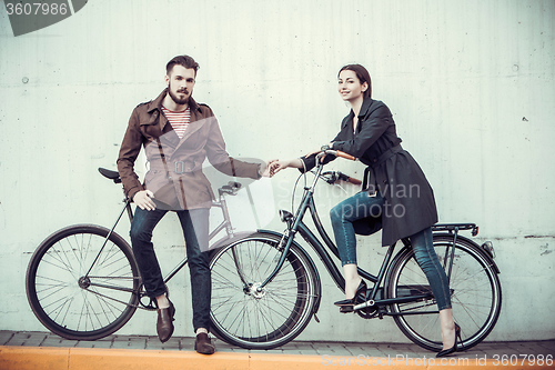 Image of Young couple with a bicycle opposite city 