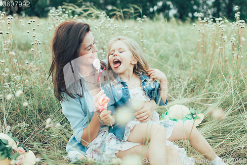 Image of The young mother and daughter on green grass background 