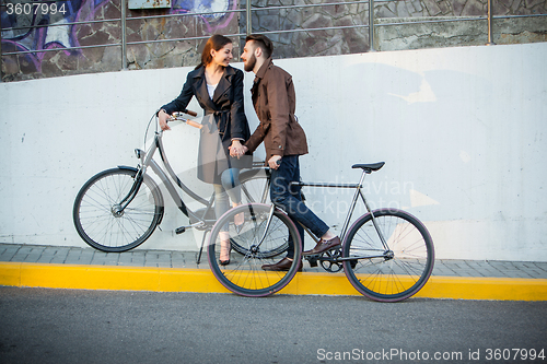 Image of Young couple with a bicycle opposite city 