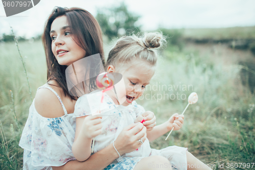 Image of The young mother and daughter on green grass background 