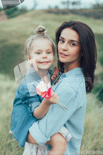 Image of The young mother and daughter on green grass background 