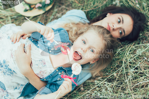 Image of The young mother and daughter on green grass background 