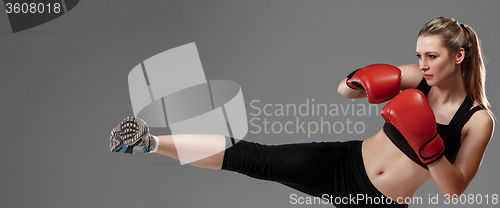 Image of beautiful woman is boxing on gray background