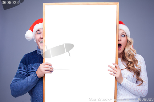 Image of Christmas couple holding white board with empty copy space 