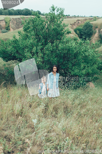 Image of The young mother and daughter on green grass background 